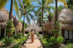 a woman walking down a path in front of a resort at Dhevan Dara Resort & Spa Hua Hin - Pool Villa in Hua Hin