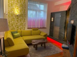 a living room with a yellow couch and a tv at Romantik Apartment mit SommerCard in Ramsau am Dachstein