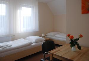 un dormitorio con 2 camas y una mesa con un jarrón de flores en Penzion Duo, en Mladá Boleslav