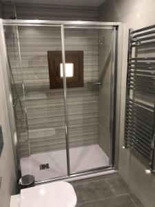 uma cabina de duche em vidro na casa de banho com um lavatório em La Riega em Potes