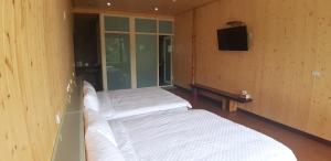a room with two beds and a television in it at Green incense Homestay in Zhuqi