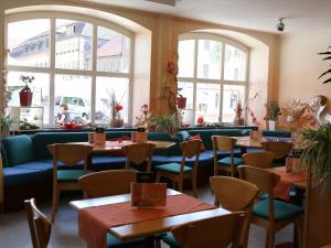 ein Restaurant mit Tischen, Stühlen und Fenstern in der Unterkunft Stadtcafé Hotel garni in Hammelburg