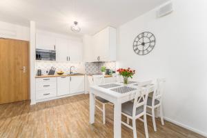 una cocina con armarios blancos y una mesa y sillas blancas. en Lily, en Kołobrzeg