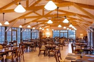 a dining room with tables and chairs and windows at Hotel Palanga Camping in Palanga