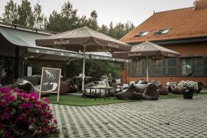
a patio area with tables, chairs and umbrellas at Palanga Camping Compensa Hotel in Palanga
