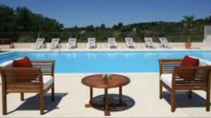 a pool with two chairs and a table and chairs at Appartement Paradou vue magnifique in Paradou