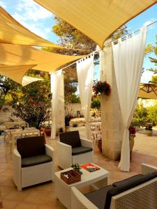 un patio con ombrelloni, tavoli e sedie bianchi di Antico Casale Il Sambuco a Manduria