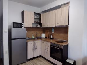 a small kitchen with a refrigerator and a microwave at Апартамент на къмпинг Градина in Chernomorets