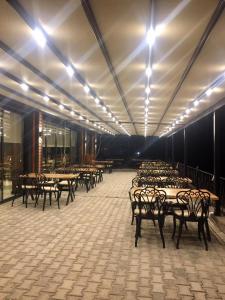 une rangée de tables et de chaises dans une pièce éclairée dans l'établissement Şavşat Karagöl Hotel, à Savsat