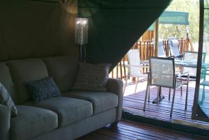 uma sala de estar com um sofá e uma mesa num alpendre em Beka Idube Bushveld Retreat em Cullinan