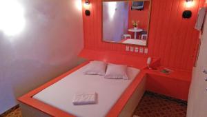 Baño rojo con banco y espejo en Motel Cisne Blumenau (Adult Only), en Blumenau