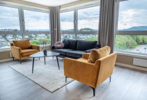 a living room with a couch and chairs and windows at Frogner House - Sirkus Renaa in Stavanger