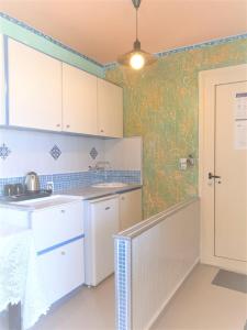 uma cozinha com armários brancos e papel de parede verde em Room in Studio - It Is So Quiet And Peaceful And Very Relaxing em Hersonissos