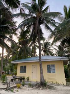 a yellow house with a picnic table and palm trees at Borawan Island Resort by Cocotel in Quezon