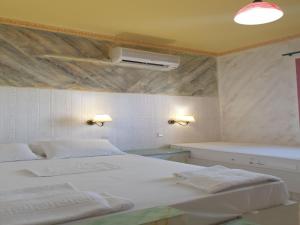 a white bedroom with two beds and a fan at Room in Apartment - Spacious Room in Creta for 3 people, with Ac, Swimming Pool and Nature in Hersonissos