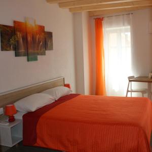 a bedroom with a bed with an orange blanket at B&B Al Portico in Telve