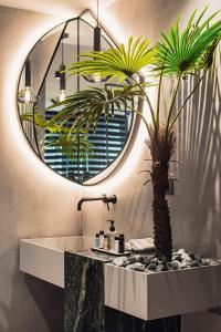 a bathroom with a sink and a mirror and a palm tree at Project 3 Urban Chic Hotel in Athens