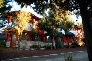 una casa roja con un banco delante en Bungalows Maniu en San Carlos de Bariloche