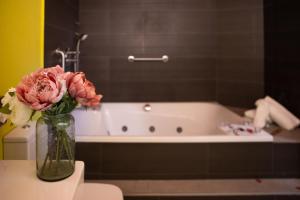 a vase of flowers sitting on a table next to a bath tub at RVHotels Hotel Palau Lo Mirador in Torroella de Montgrí