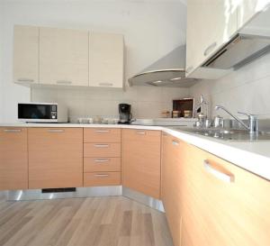 cocina grande con armarios de madera y microondas en Gardenia Apartment Ossuccio, en Ossuccio