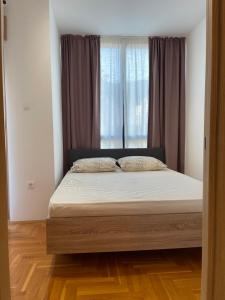 a bed in a room with a large window at Apartman 12 Jelena Anžujska in Zlatibor +19 photos