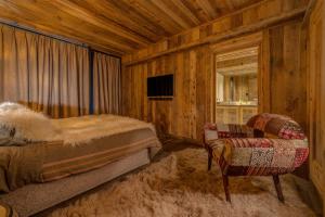a bedroom with a bed and a chair at Chalet Carte Blanche Katmaï - Val d'Isère in Val dʼIsère