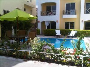 a pool with a table and an umbrella and a building at Casa Vacanze Dume in Bayahibe