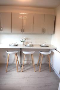 a kitchen with a table and two stools at Kelpies Serviced Apartments- Jamieson in Stenhousemuir