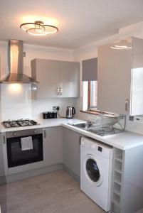 a kitchen with a washing machine and a washer at Kelpies Serviced Apartments- Jamieson in Stenhousemuir