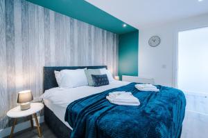 a bedroom with a large bed with a blue blanket at Rest & Recharge at The Station Apartments in Manchester