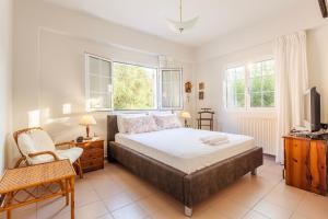 um quarto com uma cama, uma cadeira e uma televisão em Casa Nebari Seaside Retreats - Fully Equipped, Ideal Spot em Petalidi