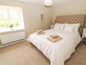 a bedroom with a large white bed with towels on it at Sgubor in Holyhead