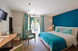 a bedroom with a blue wall and a bed and a desk at Hotel Saint-Amour in Durbuy