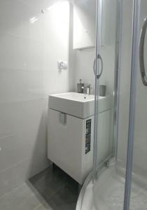 a white bathroom with a sink and a shower at Pokoje Noclegi Brzozowski in Wysokie Mazowieckie