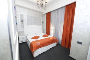 a bedroom with a white bed with an orange blanket at Hotel Roma & Tours in Yerevan
