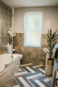 a bathroom with a tub and a toilet and a plant at The Rose Luxury Self Catering Accommodation in Armagh