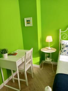 1 dormitorio con paredes verdes, mesa y cama en B&B Stella Scugnizza, en Nápoles