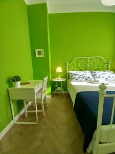 1 dormitorio con paredes verdes, 1 cama y escritorio en B&B Stella Scugnizza, en Nápoles
