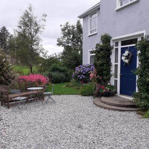 a house with a blue door and a table and chairs at Brook Lodge in Glenties