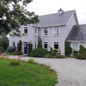 a white house with a blue door at Brook Lodge in Glenties