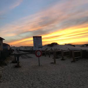 a sign in the sand with a sunset in the background at La cabane de Biscarrosse in Biscarrosse-Plage