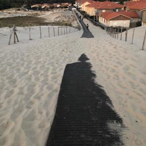 a shadow of a person on a boardwalk in the snow at La cabane de Biscarrosse in Biscarrosse-Plage