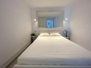 duże białe łóżko w pokoju z oknem w obiekcie Tossa Center Attic & Terrace w Tossa de Mar