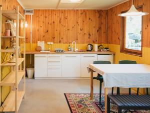 uma cozinha com paredes de madeira e uma mesa e cadeiras em Pustelnia Supraśl - domki nad rzeką em Supraśl