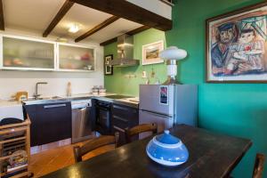 eine Küche mit grünen Wänden, einem Tisch und einem Kühlschrank in der Unterkunft Le Rose di Montagnana in San Gimignano