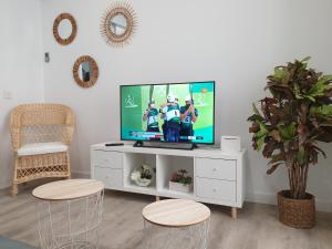 telewizor siedzący na białym centrum rozrywki z dwoma stołkami w obiekcie Sherryflat Cádiz w Kadyksie