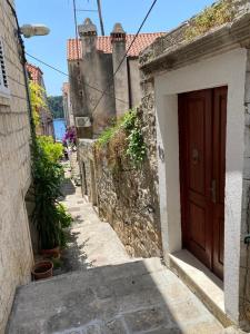 an alley with a brown door on a building at Apartments Marta in Cavtat