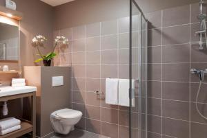 een badkamer met een douche, een toilet en een wastafel bij Nehô Suites Porte de Genève in Annemasse