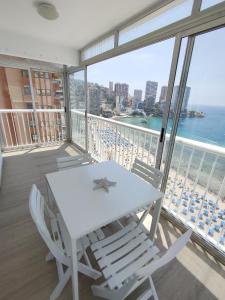 biały stół i krzesła na balkonie z widokiem na ocean w obiekcie Apartamento Veracruz - Primera Linea de Playa w mieście Benidorm