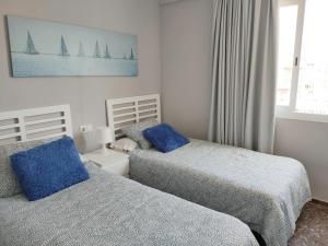 sypialnia z dwoma łóżkami i niebieskimi poduszkami w obiekcie Apartamento Veracruz - Primera Linea de Playa w mieście Benidorm